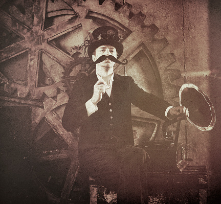 Vintage style Steampunk man holding up a fake mustache to his face.