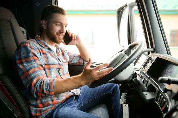 istock Young professional driver communicating over mobile phone while driving a truck. 1540100704
