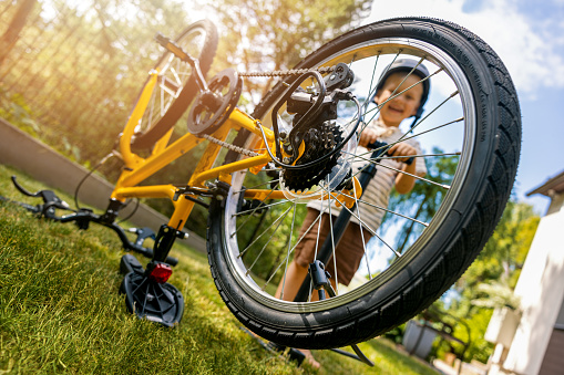 boy inflating bicycle tire with air pump at home backyard. bike maintenance
