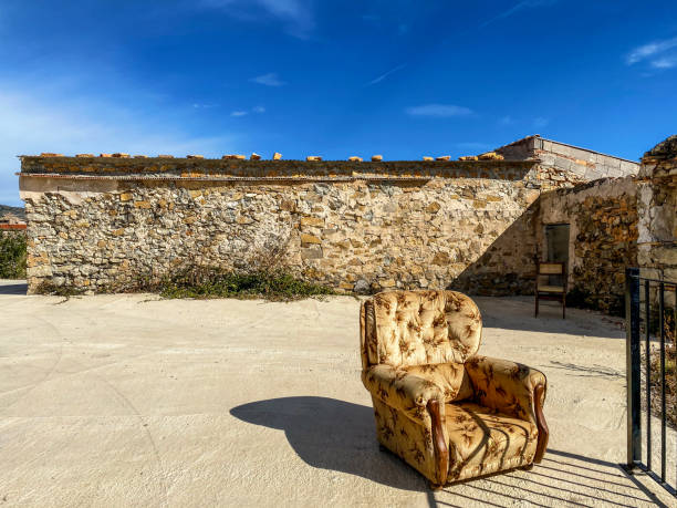 Lonely armchair over concrete flooring in front of rock structure facing the sun