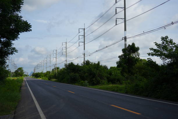High voltage poles with street road. Power lines on utility tower and cable wires in energy electric technology