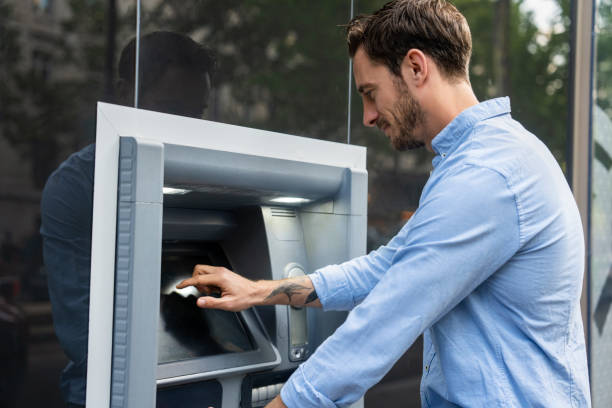 istock Young adult man using and touching ATM screen 1540157134