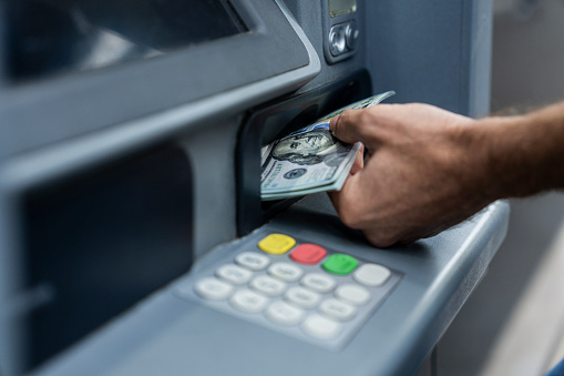 Close up shot of man depositing money on ATM