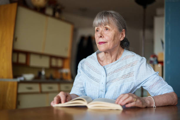 istock Thoughtful senior woman reading book at kitchen 1540161177