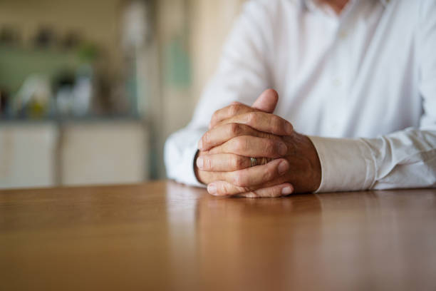 istock Senior man's hands clasped leaning on wooden table 1540161231