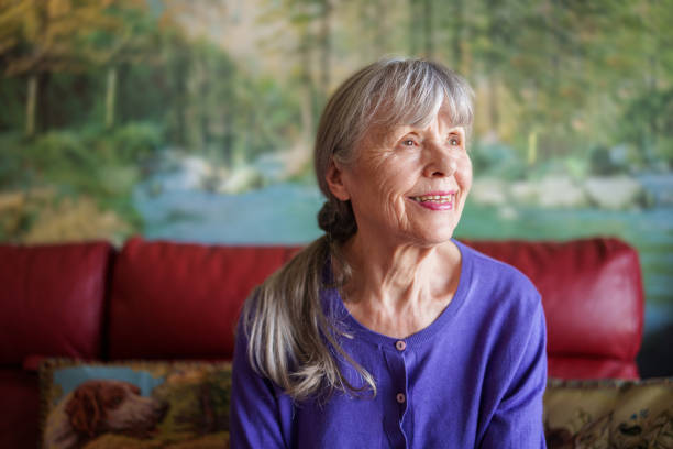 istock Senior woman smiling while looking up in living room 1540163678
