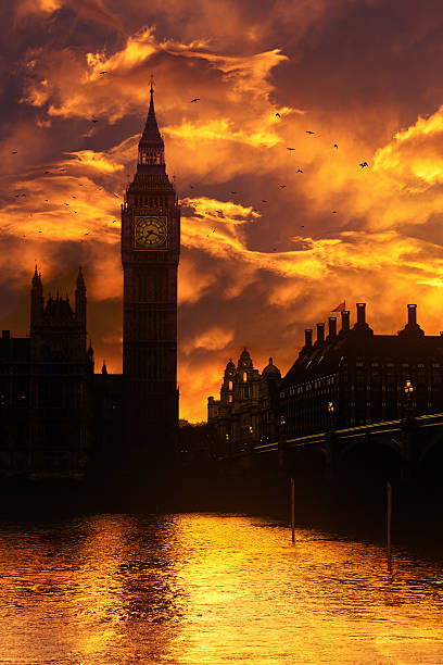 Big Ben in London at dusk - fiery sunset and flock of birds
