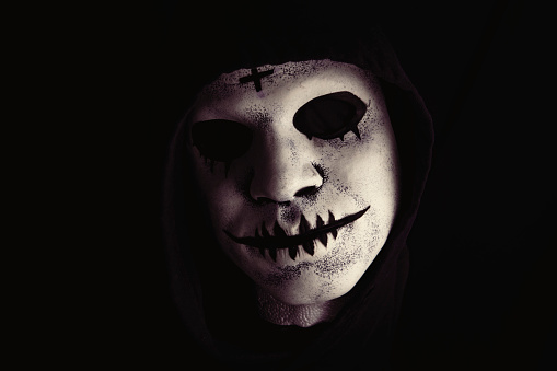 A creepy Halloween mask in the shadows of the night.