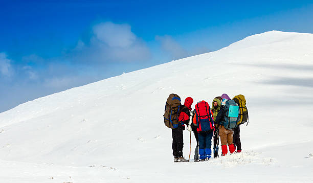 istock A group of hikers huddling in the snow under a blue sky 154020969