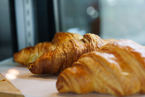 Close-up shot of delicious brown bread croissants Inside the shop, there are 3 machines ready for customers to come in and order.