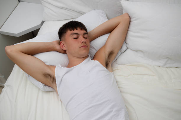 Young single male adult asleep in his clothes, on top of his bed