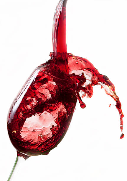 istock Red wine pouring into glass, isolated on white background 154024287