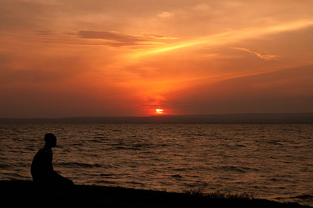 man contemplates 夕日 - lake victoria ストックフォトと画像