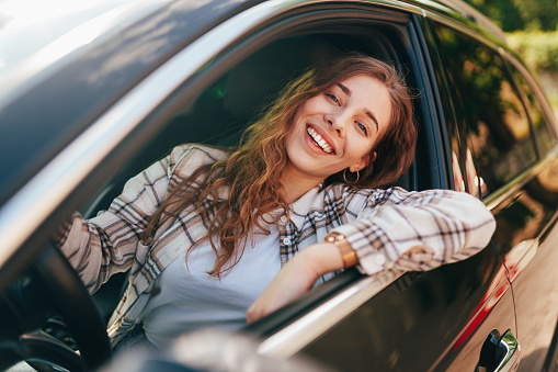Happy smiling woman inside a car driving in the street close up