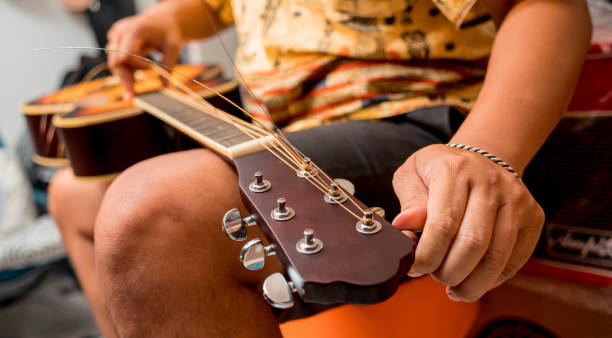 ギターショップでクラシックギターの弦を変える若いミュージシャン - 16017 ストックフォトと画像