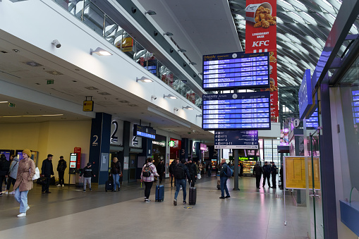 Poznan, Poland - April 19, 2023: Inside the main station in Poznań, people with bags and suitcases move around the station, a modern electronic board with a transport schedule hangs at the top.