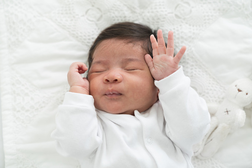 Top view of Newborn baby sleeping with blanket on white bed. Infant lying on white bed. Asian newborn baby