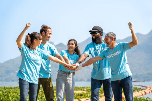 istock Group of happy volunteers joining hands stack together and raising hands with smile 1540290157