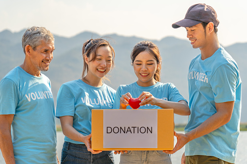 group of diverse volunteers carrying donation box and a red heart charitable working together for campaign donations to help underprivileged people by donate food, clothing or support education
