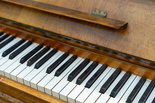 In a horizontal view, piano keys are captured near a window, with natural sunlight shining on them. This setup creates a diminishing perspective and adds a touch of warmth to the scene.