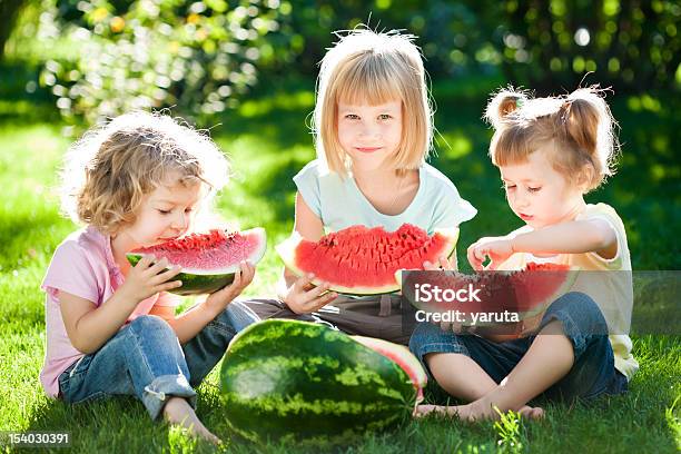 Three Blonde Girls Enjoying A Watermelon At A Picnic Stock Photo - Download Image Now