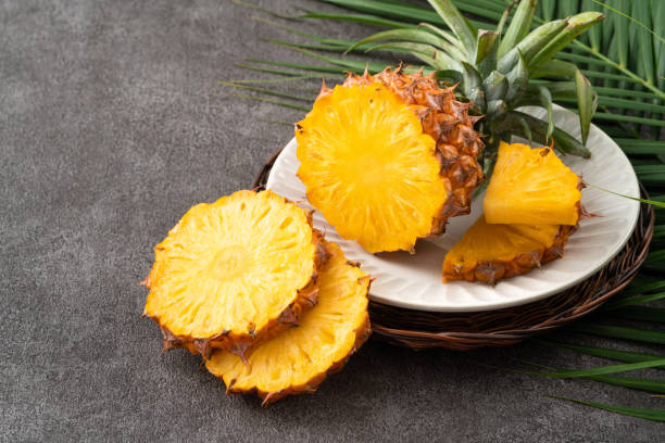 istock Fresh cut sliced pineapple in a plate over dark gray table background. 1540307292