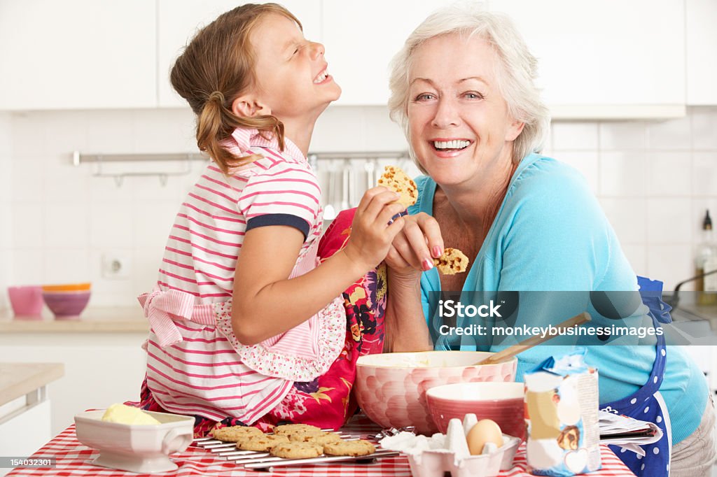 Grandmother and granddaughter laughing and baking in kitchen Grandmother And Granddaughter Baking In Kitchen Smiling And Laughing. Cake Stock Photo