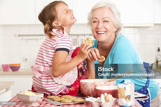 Grandmother And Granddaughter Laughing And Baking In Kitchen Stock Photo - Download Image Now