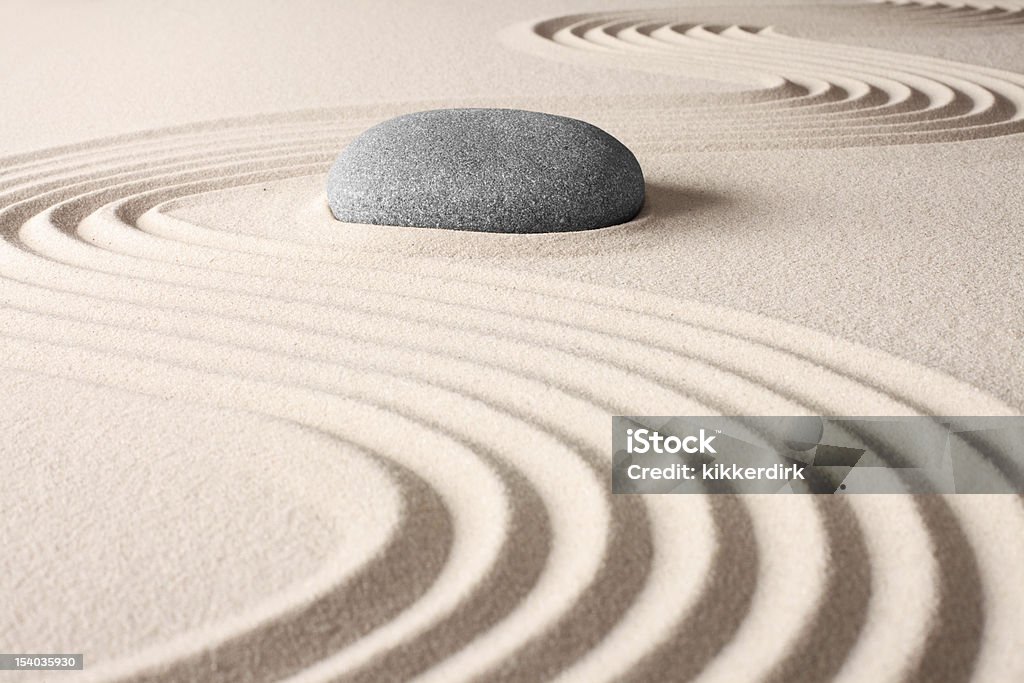 A Japanese zen garden with lines in sand and a gray rock zen buddhism spiritual japanese rock garden abstract harmony and balance concept for purity sand and stone Sand Stock Photo