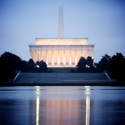 Classic Washington DC view of the Lincoln Memorial and Washington Monument reflecting in the Potomac River at dawn.