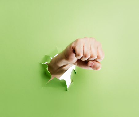 Man punching through green cardboard with his fist.