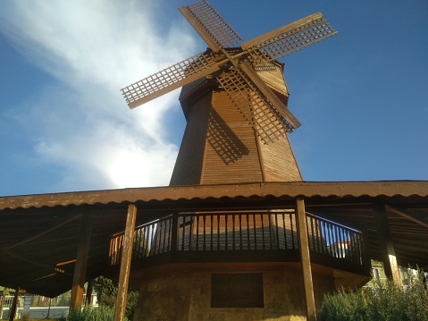 The wooden windmill has become a recognizable character in a novel by a Spanish writer on partly cloudy sky background