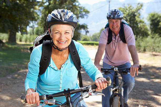 pareja senior en paseo en bicicleta de país - action mature adult bicycle senior couple fotografías e imágenes de stock