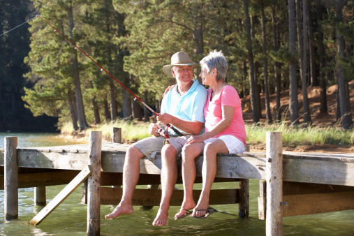 Senior couple sitting on jetty together fishing