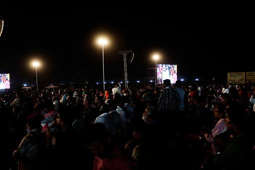 Coimbatore, Tamil Nadu, India –  February 18, 2023: Group of people gather together during mahashivratri festival celebration event at night in front of Aadiyogi Lord Shiva 112 feet tall statue.