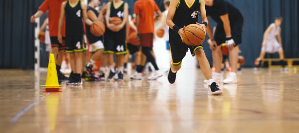 jovens jogadores de basquetebol numa equipa em treino de treino. os meninos praticam basquete com o jovem treinador. unidade de treinamento de basquete para jovens jogadores - basketball child dribbling basketball player - fotografias e filmes do acervo