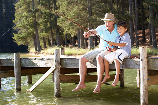 senior homme pêche avec petit-fils - fishing lake grandfather grandson photos et images de collection