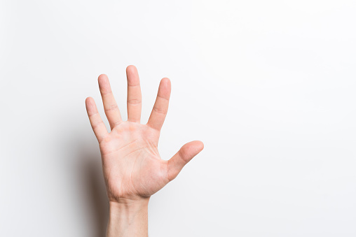 A close-up of a Caucasian male hand shows gesture number five or greeting isolated on a white studio background.