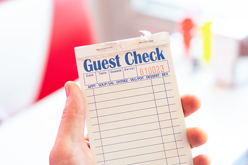 Close-up of an order pad held in the left hand, ready to write down a customer order in a traditional diner.