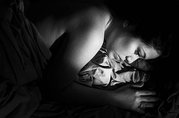 Depressed woman lying on a bed stock photo