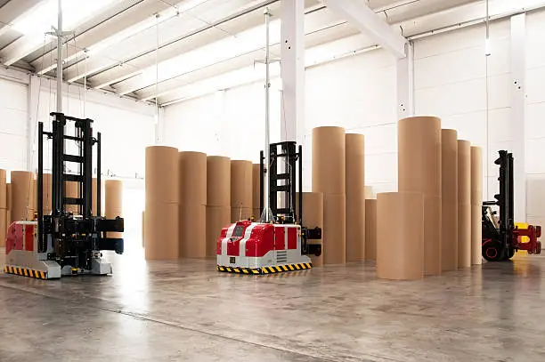 Photo of The inside of a warehouse with large tubes for paper