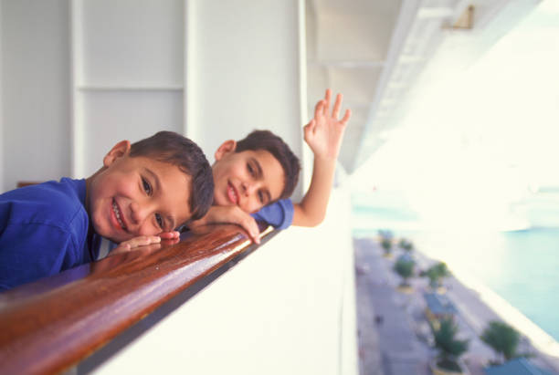 Two kids on a cruise ship looking out from balcony stock photo