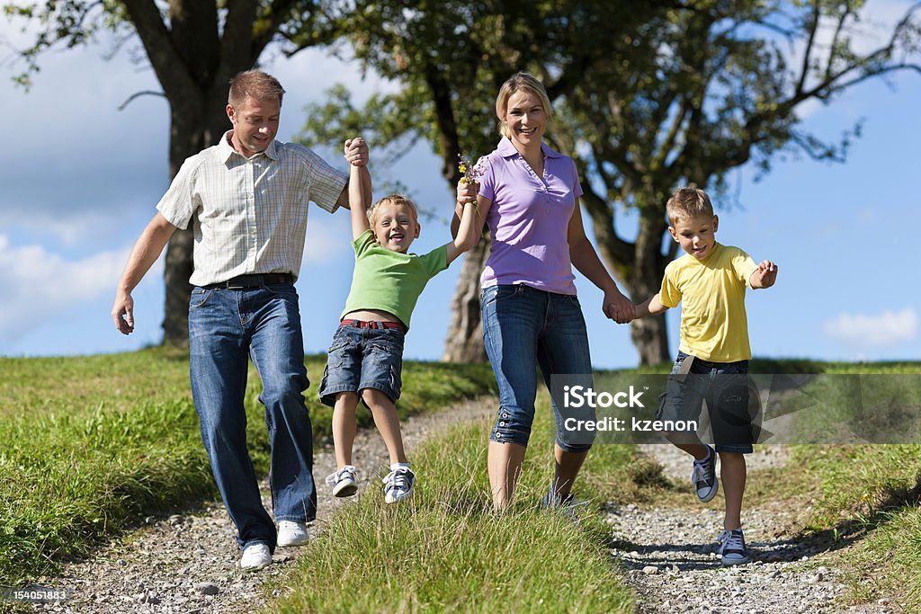 Famiglia all'aria aperta è in esecuzione su un sentiero sterrato - Foto stock royalty-free di Adulto