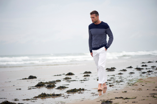 Young Man Wearing Striped Sweater Walking on the Beach