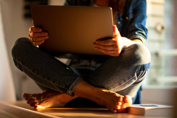 entrepreneur woman sitting on the floor of her house teleworking with her laptop with gray wall and copy space