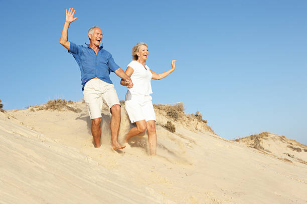istock Senior Couple Enjoying Beach Holiday Running Down Sand Dune 154057436