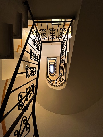 Black iron stair railing, leading up a staircase, in an interior setting