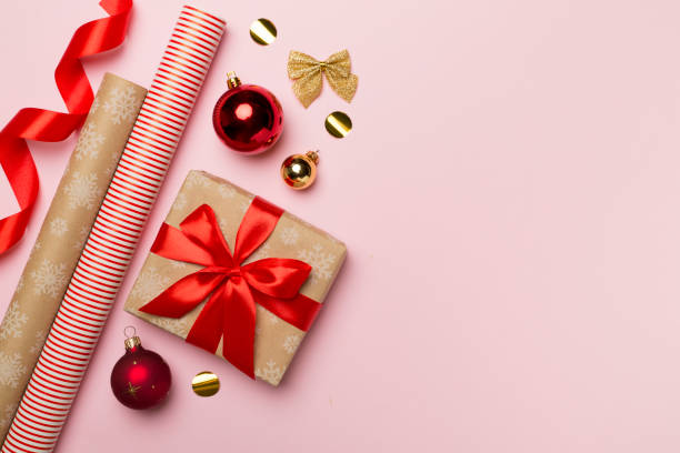 Gift boxes, paper's rools and decorations on color background, top view