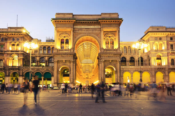 Galleria Vittorio Emanuele presso Piazza del Duomo Milan Italy Galleria Vittorio Emanuele II at Piazza del Duomo in Milan, Italy, the famous luxury shopping mall. Night Scene with illuminated building, long exposure, unrecognizable motion blurred people rushing through. milan stock pictures, royalty-free photos & images