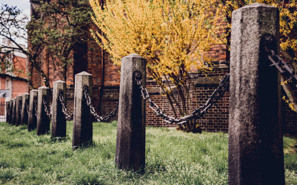 istock Old stone posts with chains on a background of green grass 1540628900